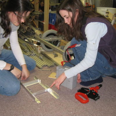 Brittany F. helping Carissa F. with the battery box.